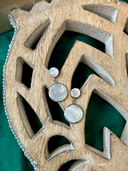 Silver earrings with pearl on a Wooden decorative item with a green fabric background, luna pearl earrings,